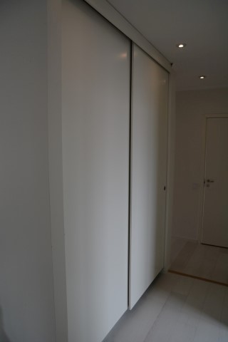 vit garderob med skjutdörrar måttanpassad i nisch från vägg till vägg och golv till tak